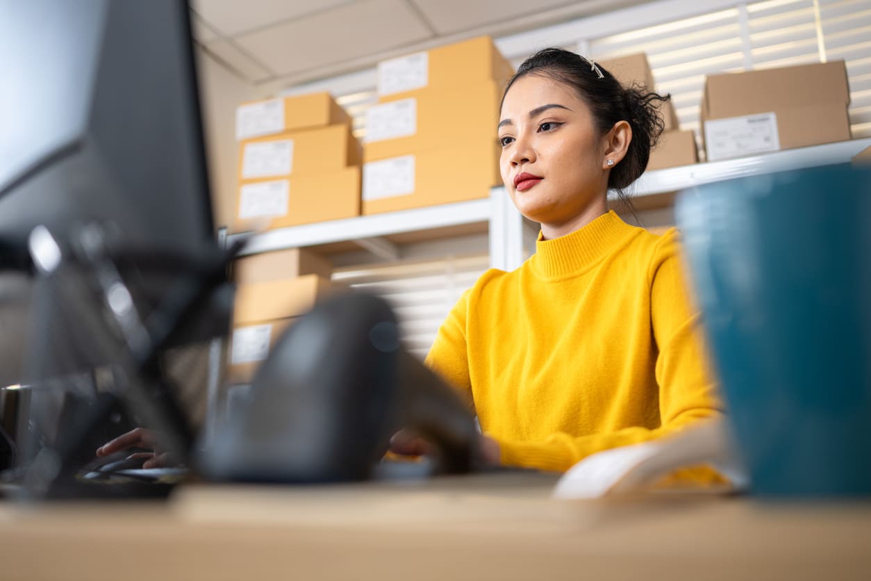 female-warehouse-staff-focused-on-computer-screen-managing-online-orders