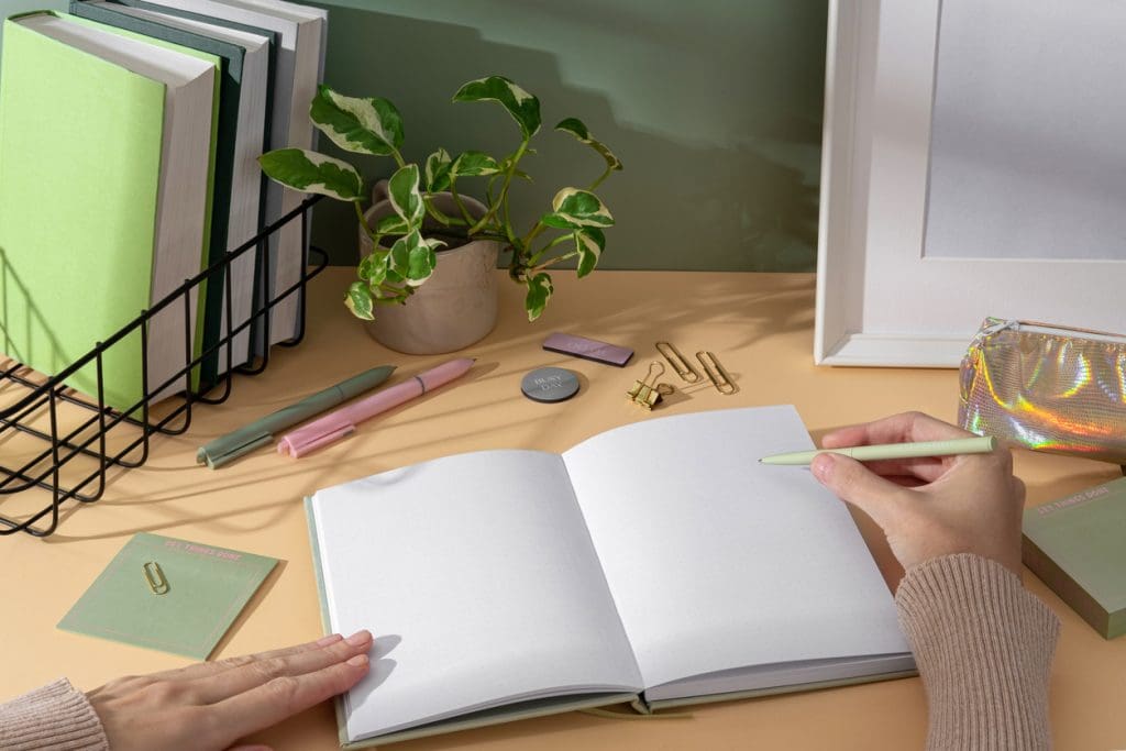 elegant-lightgreen-notebook-with-stationery-sticky-notes-perfect-for-notes-sketches-and-organizing-thoughts-young-woman-writing-notes-in-a-notebook-organized-workspace-productive-study-setup